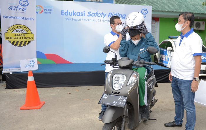 Director Asuransi Astra, Mulia K. B. Siregar dan Adi Sepiarso membantu pemakaian safety kit kepada murid saat edukasi safety riding di SMKN 7 Makassar